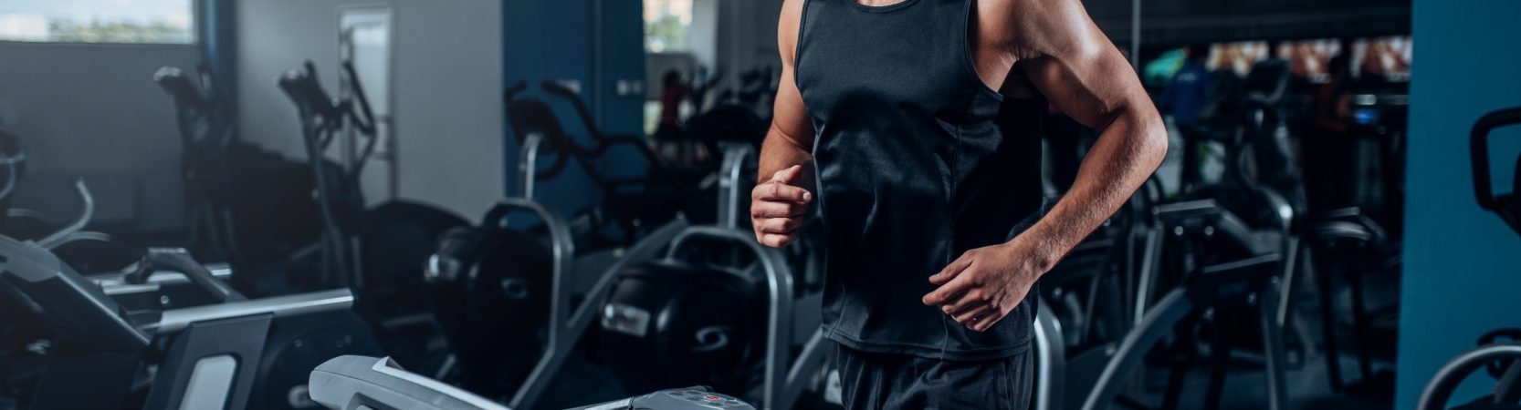 Male athlete workout on running exercise machine. Active sport training in gym